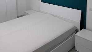 A modern bedroom with a white bed, a teal accent wall, and a hanging light fixture. - NEW LUXURY BIG APARTMENT (Pescara)