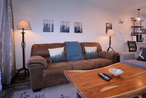 A living room with a brown sofa, two side tables, a coffee table, and a fireplace. - Emmons Ease, 2BR/2BA, Remodeled at ski resort, hot tub (Mt. Crested Butte)