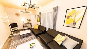 A modern living room with a black sofa, a white coffee table, and a decorative lamp.