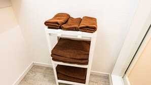 A white shelf with brown towels stacked on it.