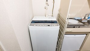 A compact, modern laundry room with a front-loading washer and dryer, a small sink, and a towel rack.