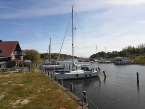 Ein Yachthafen mit vertäuten Booten, ein Gebäude mit rotem Dach und eine Rasenfläche mit Steg.