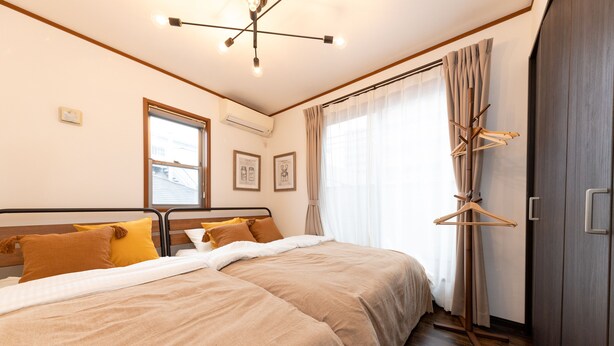 Een slaapkamer met twee bedden, een garderobe, een raam met gordijnen en een plafondlamp.