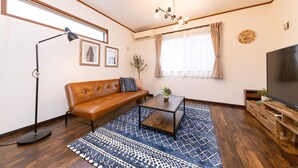 Een woonkamer met een bruine leren bank, een salontafel, een tv-meubel, een kamerkleed en een vloerlamp.