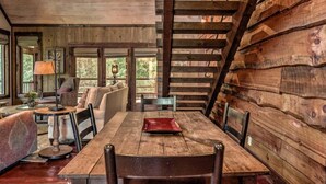 A rustic wooden interior with a dining table, chairs, a sofa, and a lamp. - Firefly Farmhouse - Riverfront | Modern | 2 Bedroom w loft (Blue Ridge)