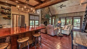 A spacious living area with a wooden bar, seating, and a stone fireplace. - Firefly Farmhouse - Riverfront | Modern | 2 Bedroom w loft (Blue Ridge)