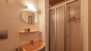 Une salle de bain avec un lavabo, un miroir et une douche.