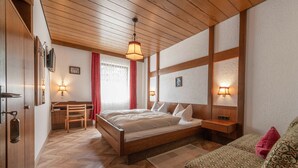 Une chambre à coucher avec un lit en bois, des tables de chevet, un bureau et un canapé à motifs.