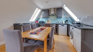 A modern kitchen with a dining area, skylights, and a washing machine.