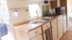 Une cuisine de taille réduite, équipée d’un évier, de placards et d’une fenêtre.