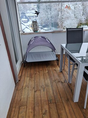 Ein Zimmer mit Holzboden, einem Fenster mit Blick auf schneebedeckte Bäume, einem Tisch mit einem Laptop und einer zeltartigen Struktur.
