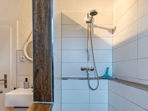 A bathroom with a shower, a sink, and a mirror.