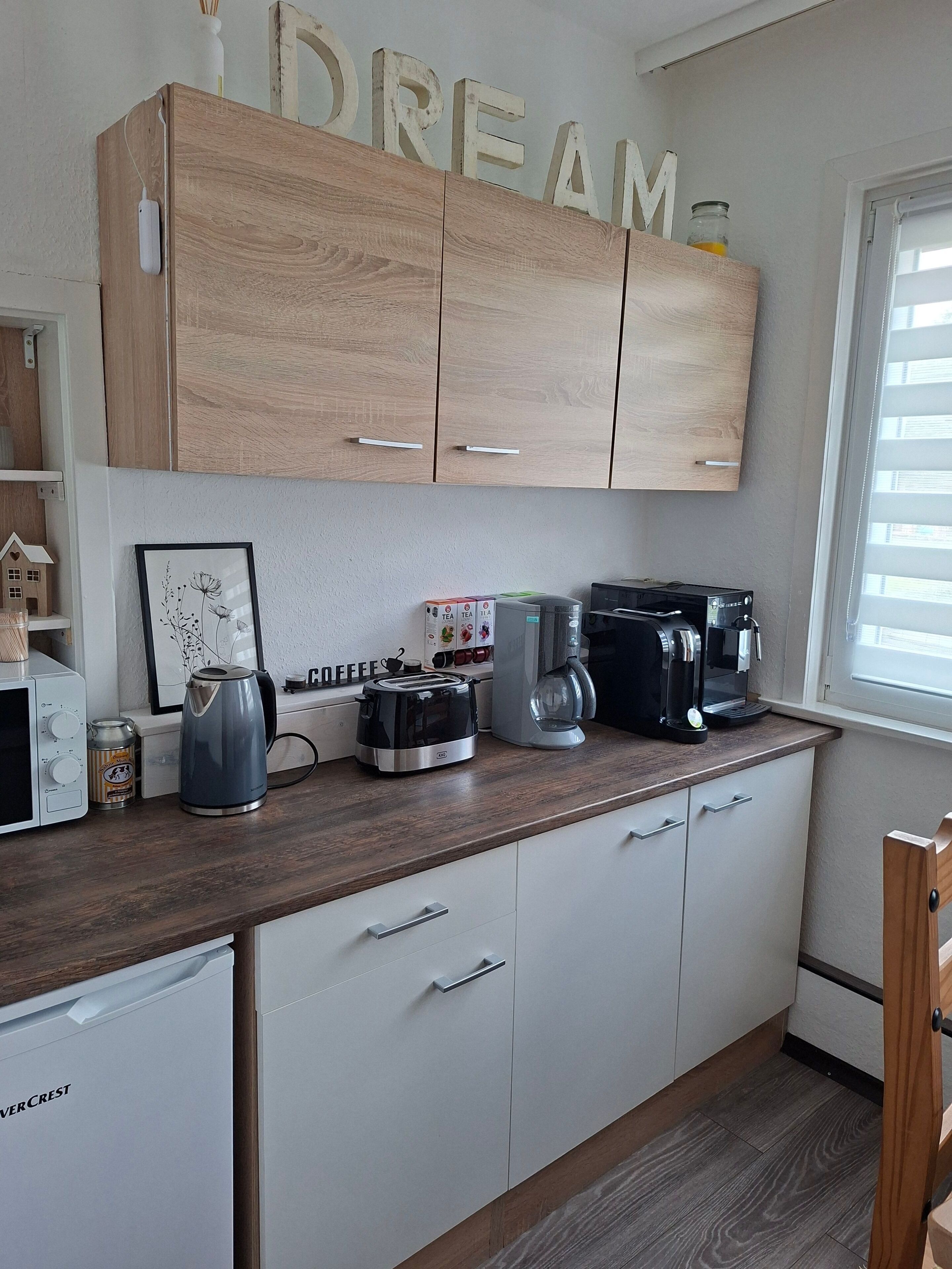Eine Küche mit Holzausstattung, einer Kaffeemaschine, einem Toaster und einem Wasserkocher.