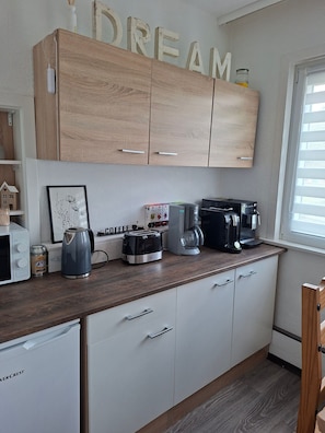 Eine Küche mit Holzausstattung, einer Kaffeemaschine, einem Toaster und einem Wasserkocher.