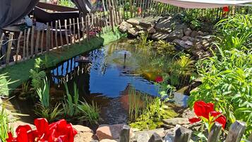 Ein Garten mit Teich, Holzzaun und roten Blumen.