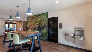 A modern meeting room with a wooden table, green upholstered chairs, and pendant lighting.