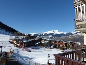 A snow-covered ski resort with wooden buildings and a mountain backdrop.