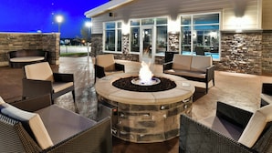 An outdoor patio with stone fire pit seating and a pool area visible through glass doors.