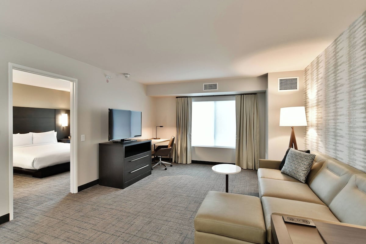 Une chambre d’hôtel avec un lit, un bureau, une télévision, un canapé et une petite table.