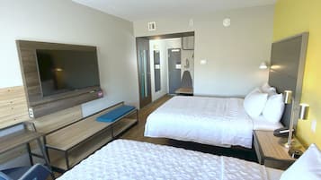 A hotel room with two beds, a TV, a desk, and a bench.