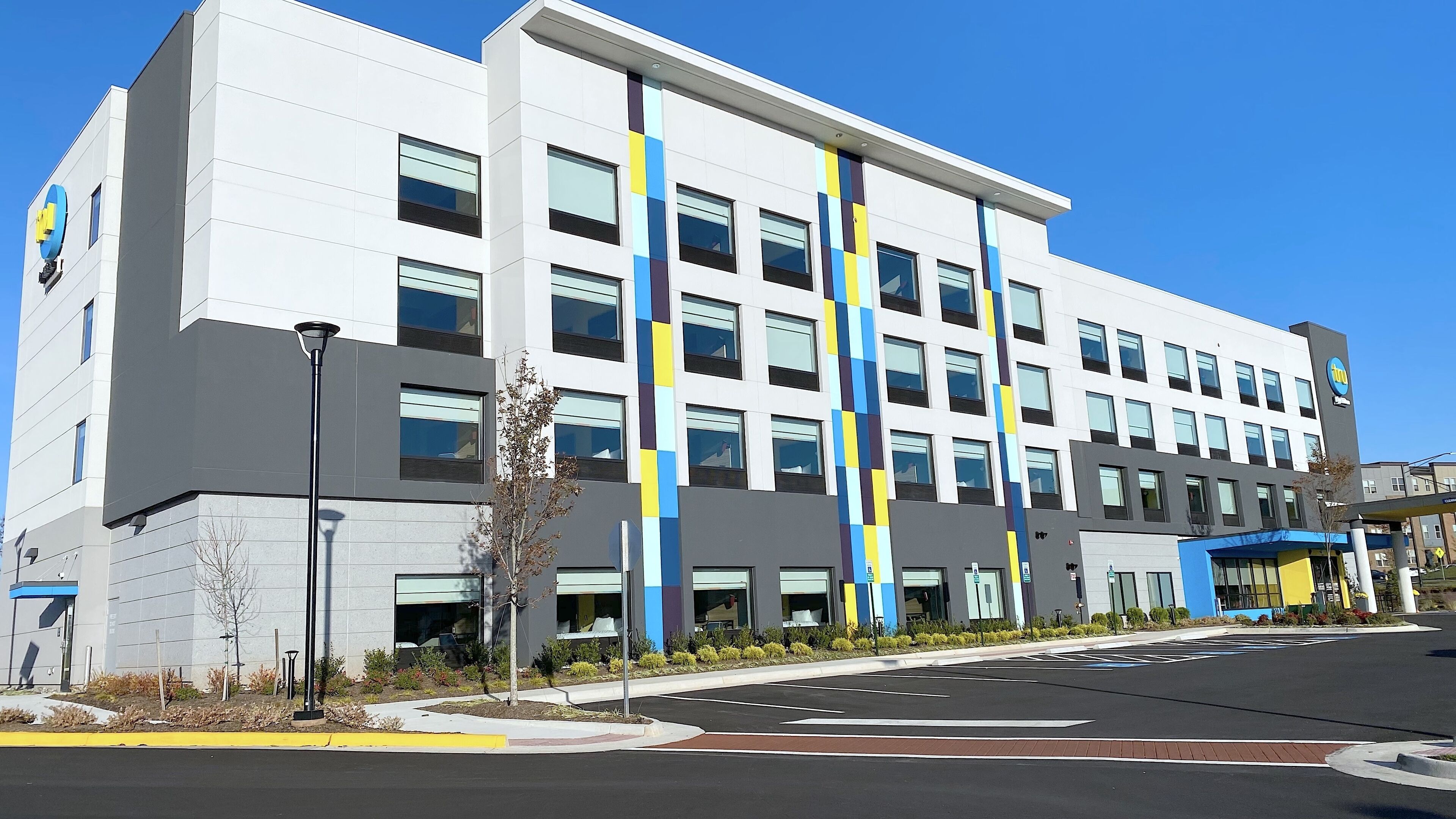 A modern multi-story building with a white facade and blue and yellow vertical stripes.