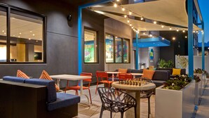 An outdoor seating area with tables, chairs, and a chess table. - Tru by Hilton Manassas (Manassas)