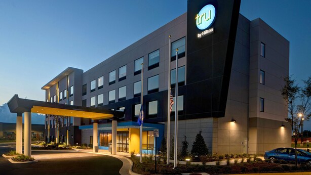 A modern hotel building with a prominent 'TRU by Hilton' sign, multiple windows, and a well-lit entrance area. - Tru by Hilton Manassas (Manassas)