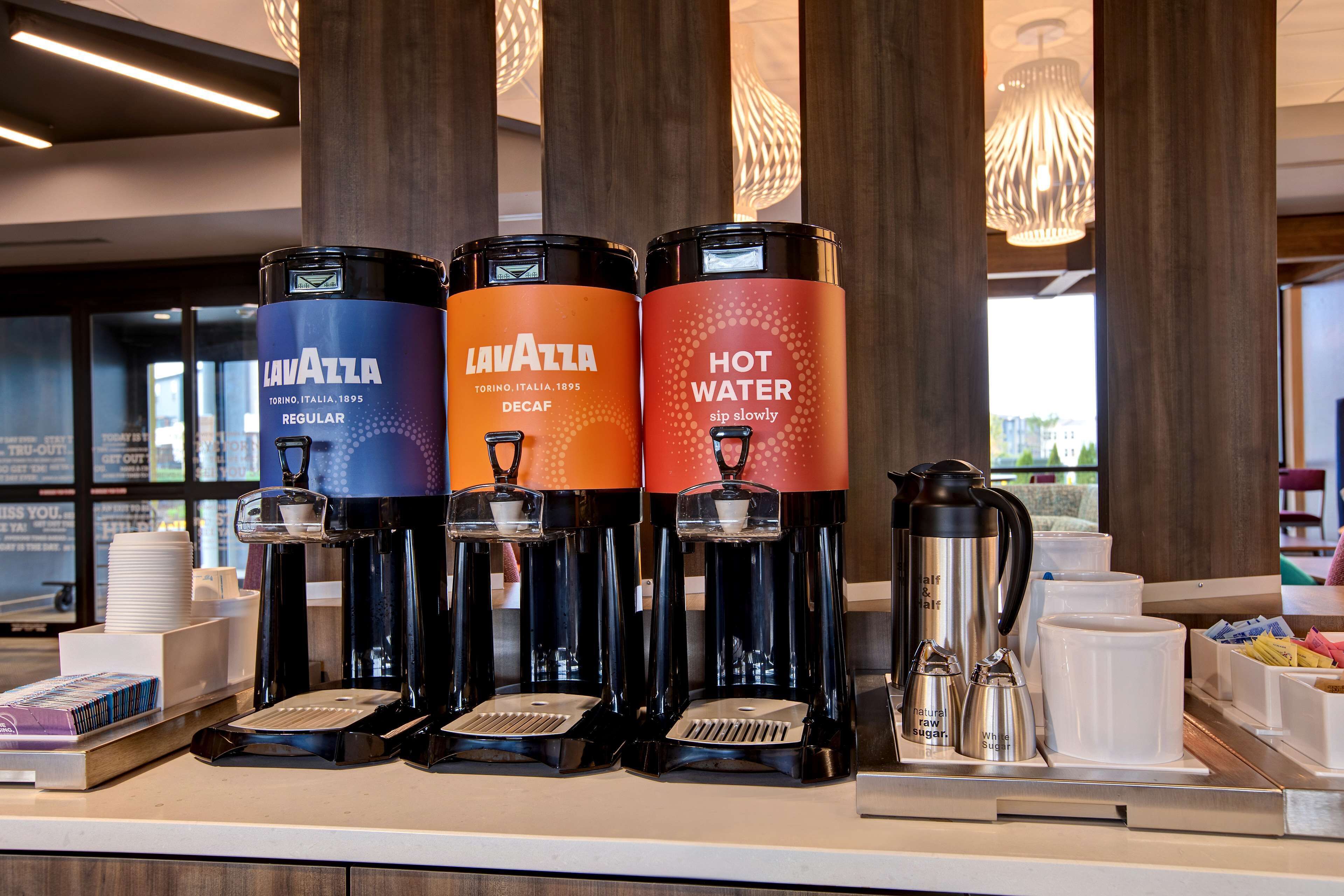 Una estación de café con tres dispensadores etiquetados 'Lavazza' y 'Agua Caliente'.