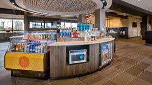 A self-service beverage station with a microwave, various drinks, and snacks. - Tru by Hilton Manassas (Manassas)
