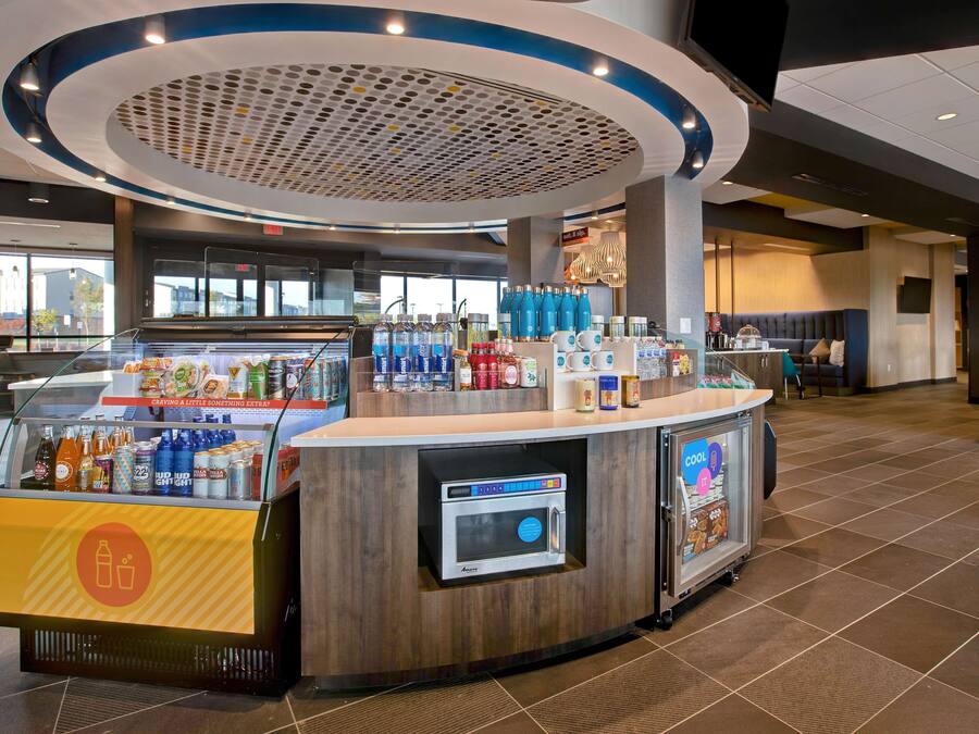 Una estación de bebidas autoservicio con microondas, diversas bebidas y aperitivos.
