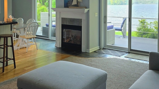Ein geräumiges Wohnzimmer mit Kamin, großen Fenstern und Seeblick.