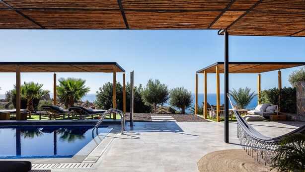 A pool area with lounge chairs and a hammock under a wooden pergola, overlooking a body of water. - Luxe Coastal Escape with Sea Views - Kumo Villa I (Rethymno)