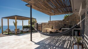 A covered outdoor area with a hammock, stone wall, and a view of the sea. - Luxe Coastal Escape with Sea Views - Kumo Villa I (Rethymno)