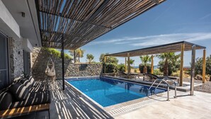 A pool area with a pergola, seating, and a stone wall. - Luxe Coastal Escape with Sea Views - Kumo Villa I (Rethymno)