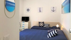 Ein Schlafzimmer mit zwei Betten, einem Fernseher, einem Schreibtisch und maritimer Dekoration.