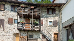 Ein Gebäude aus Stein mit einem hölzernen Balkon, einer Treppe und einer Tür.