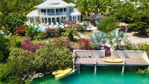 A large house with a pool, surrounded by lush greenery and palm trees. - Amazing Waterfront Villa (Providenciales)