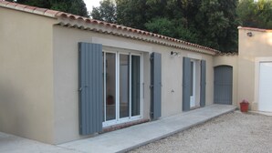 Ein Gebäude mit einer beige farbenen Fassade, grauen Fensterläden und einem Ziegeldach.