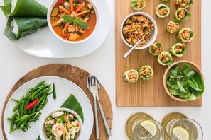 A table with various dishes including a bowl of soup, a plate of green beans, a salad, and several small cups of food.