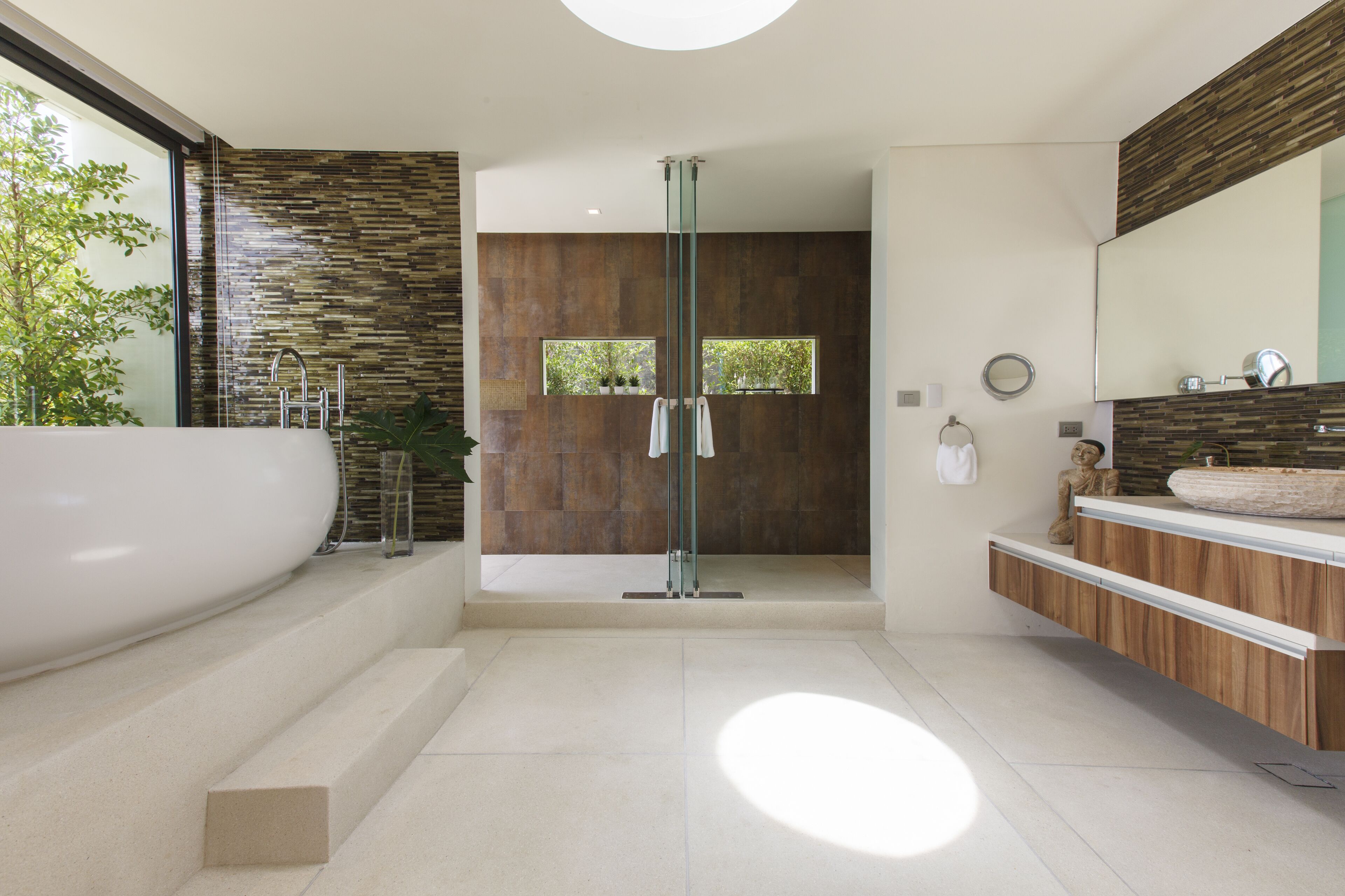 A modern bathroom with a large bathtub, a glass shower enclosure, and a wooden vanity.