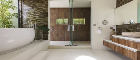 A modern bathroom with a large bathtub, a glass shower enclosure, and a wooden vanity.