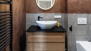 Un baño moderno con un espejo redondo, un lavabo blanco y un mueble de tocador de madera.