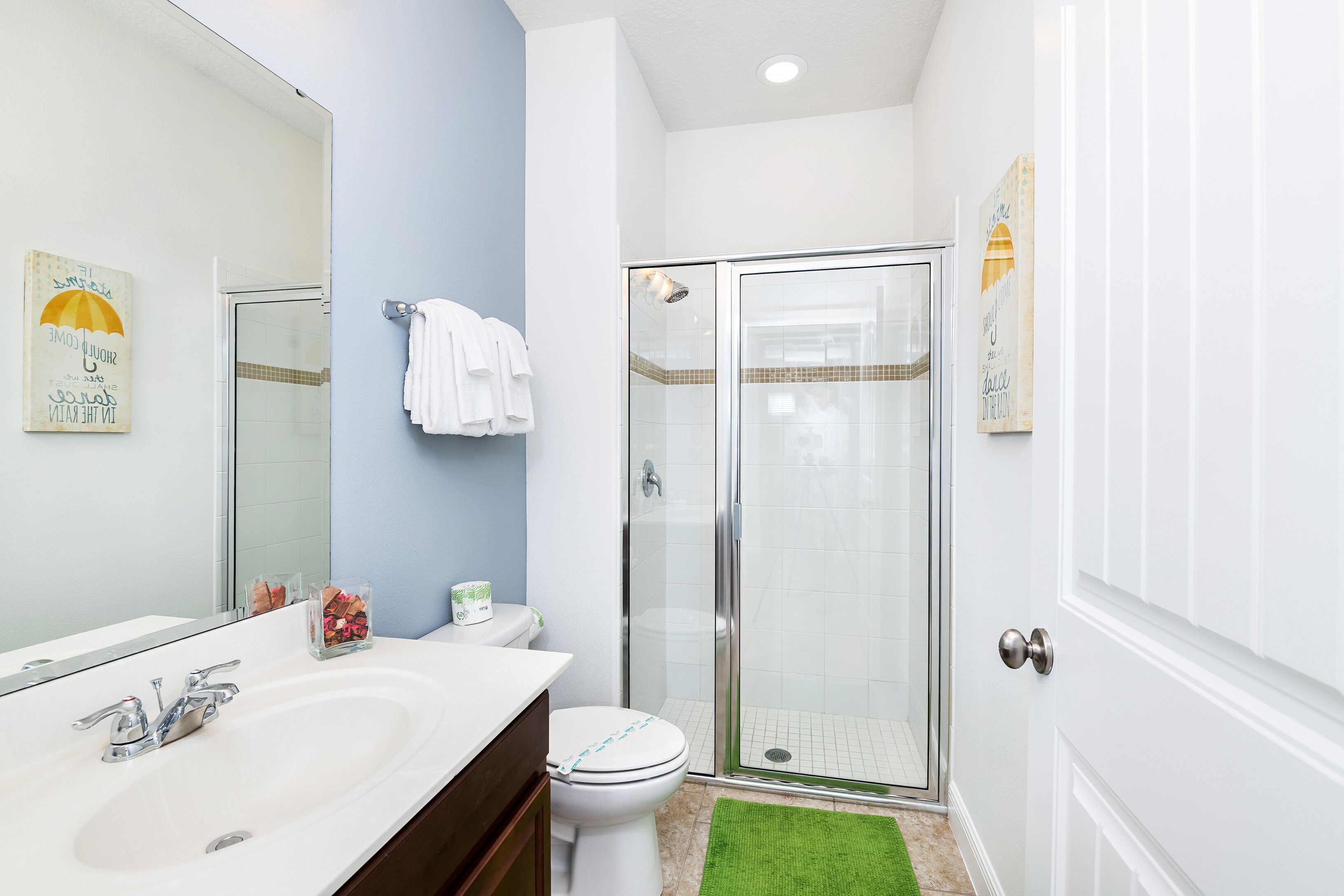 A bathroom with a glass-enclosed shower, a white sink, and a toilet.