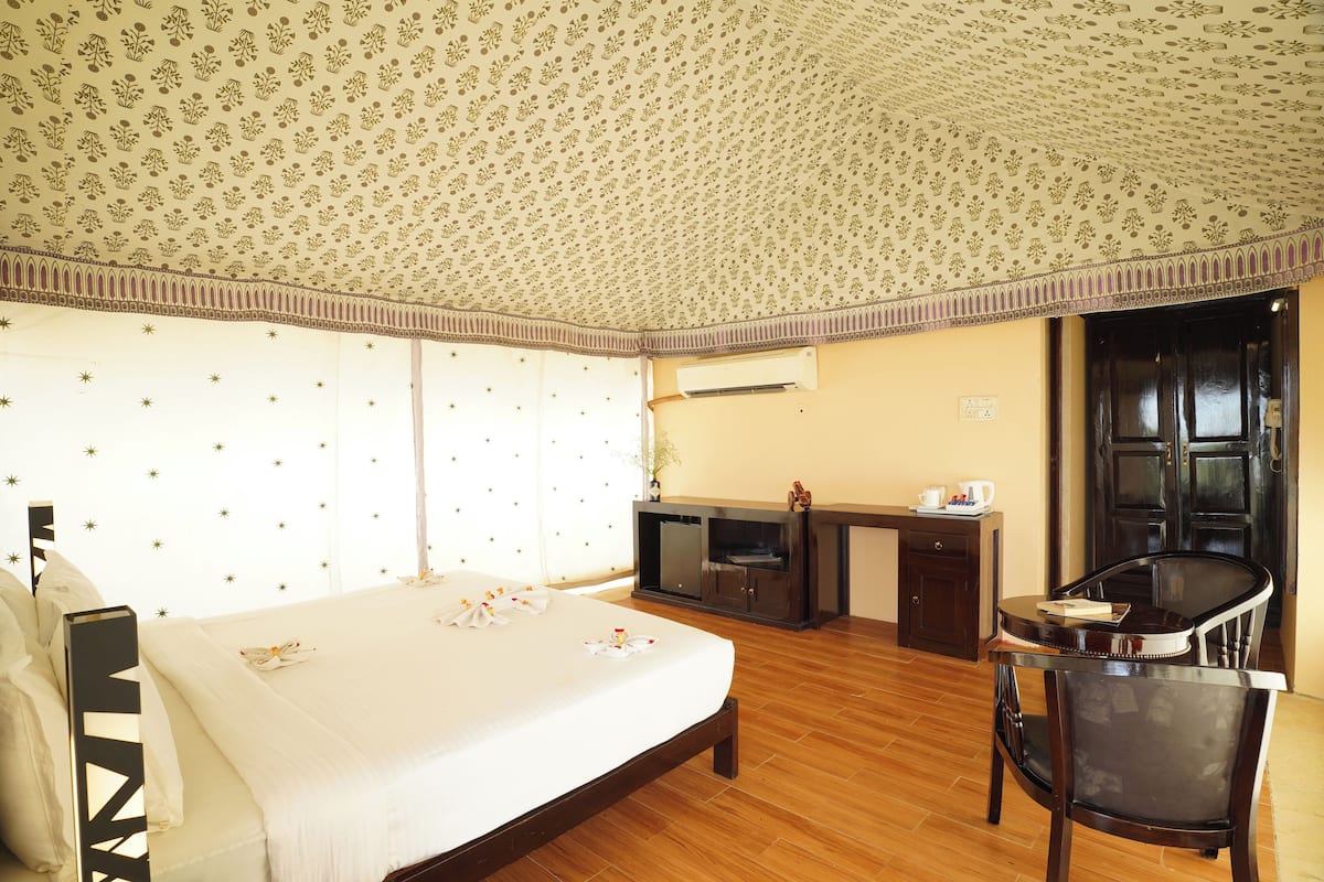 A hotel room with a bed, a desk, a chair, and a wardrobe.
