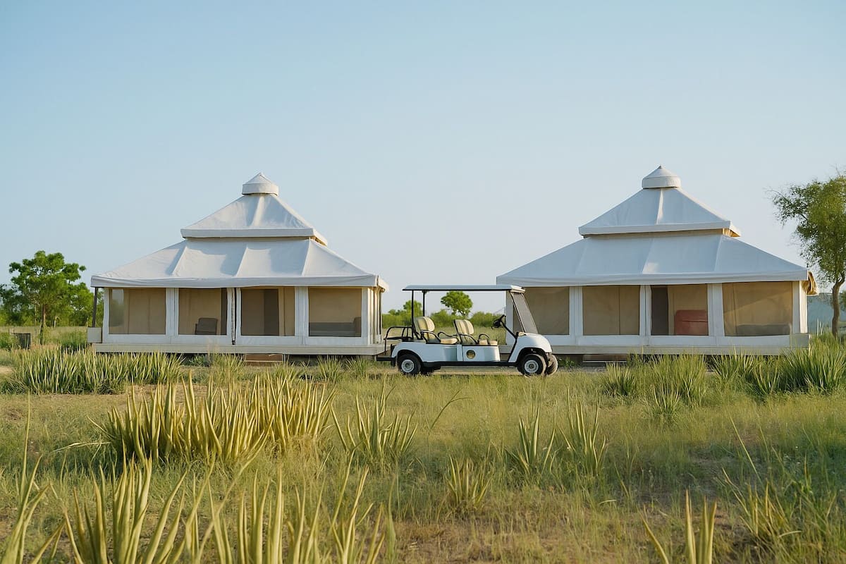 Two white tents with a golf cart parked between them.