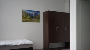 A bedroom with a bed, a wardrobe, and a picture of a mountain landscape on the wall. - Stadtpension Heilbronn (Heilbronn)