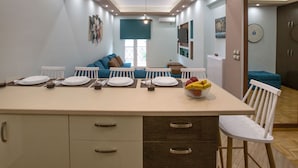 A modern kitchen with a central island, white chairs, and a dining table set for four. - Stunning Apt near Acropolis Museum by GHH (Athens)