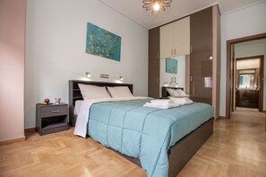 A modern bedroom with a large bed, a nightstand, a mirror, and a door leading to another room. - Stunning Apt near Acropolis Museum by GHH (Athens)