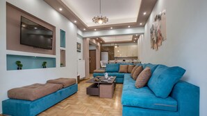 A modern living room with a blue sofa, a coffee table, and a TV mounted on the wall. - Stunning Apt near Acropolis Museum by GHH (Athens)
