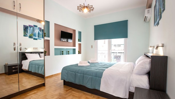 A modern bedroom with a large bed, a mirror, a TV, and a window with a view. - Stunning Apt near Acropolis Museum by GHH (Athens)